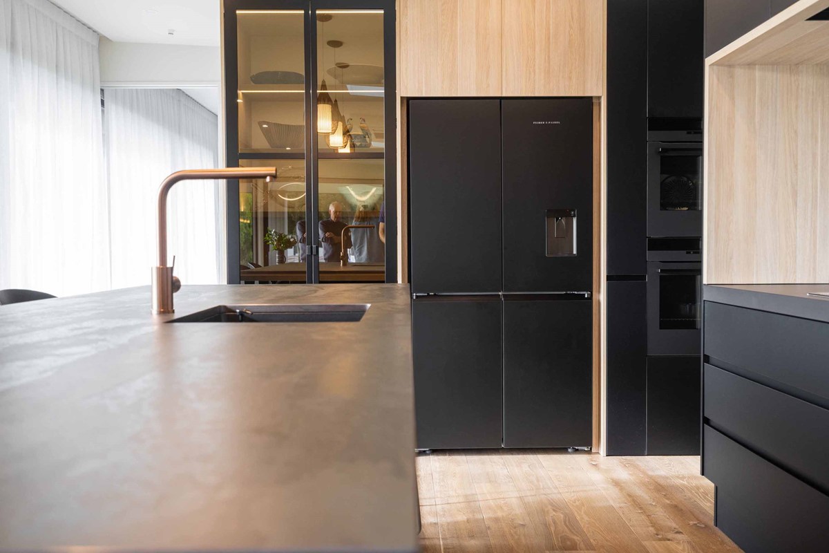 A closer look into Tony & Janie's kitchen which provides the perfect contrast of black and oak colours. Right down to their charcoal Fisher & Paykel fridge freezer.