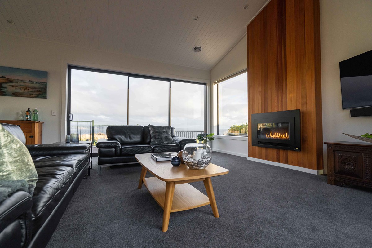 The living area of Judy and Alan's home with a beautiful timber feature wall fireplace. The view over Lake Taupo cannot be missed from this living area.