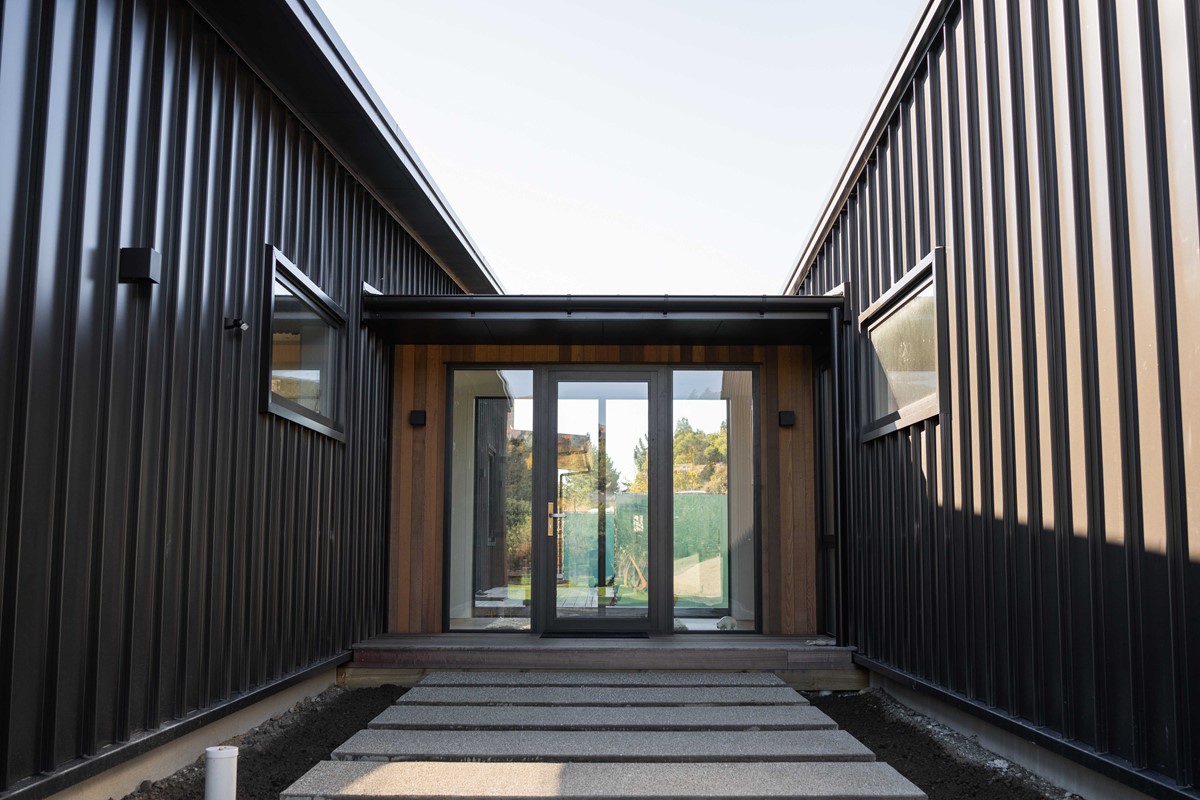 The front entrance to Colleen & John's home. Dark vertical cladding contrasting with a beautiful timber surrounding the front door.