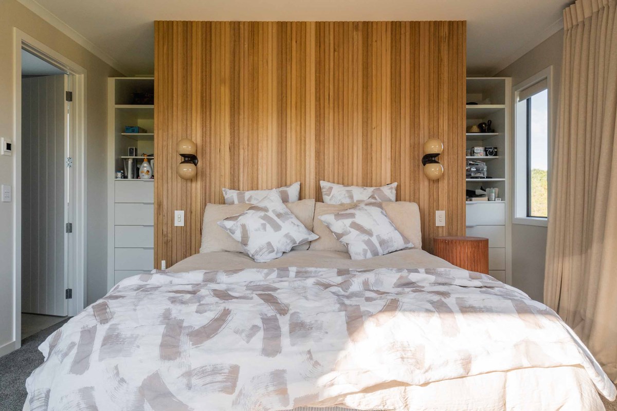 The master bedroom and stunning wooden feature wall which reflects the wooden features throughout the home. Natural tones are a win for Laura and Shaun.