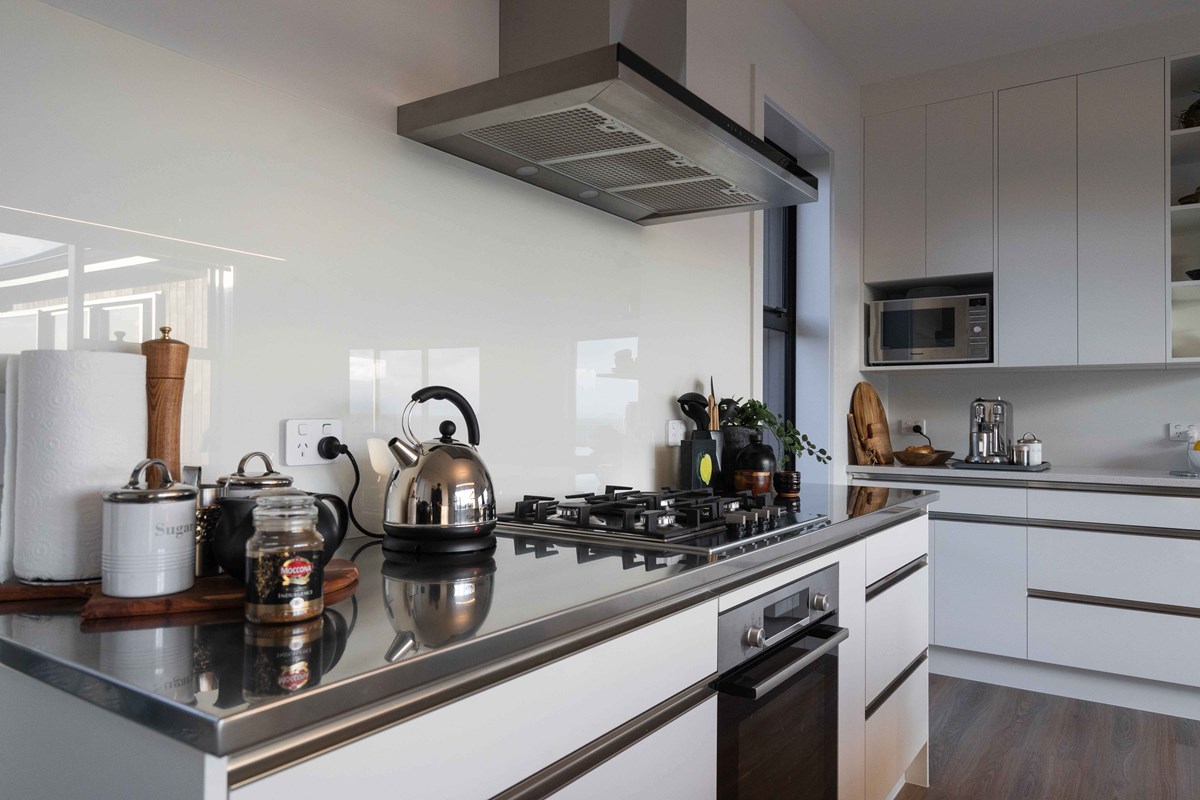 One of Judy's favourite parts of the kitchen, the gas stove top. A crisp white splashback and joinery contrasts with the timber features throughout the home and black decor.